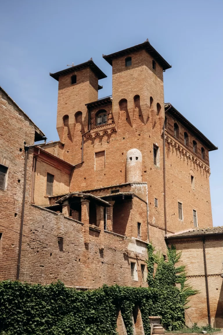 Historic brick towers of Castello di San Fabiano rising against clear blue sky in Tuscany