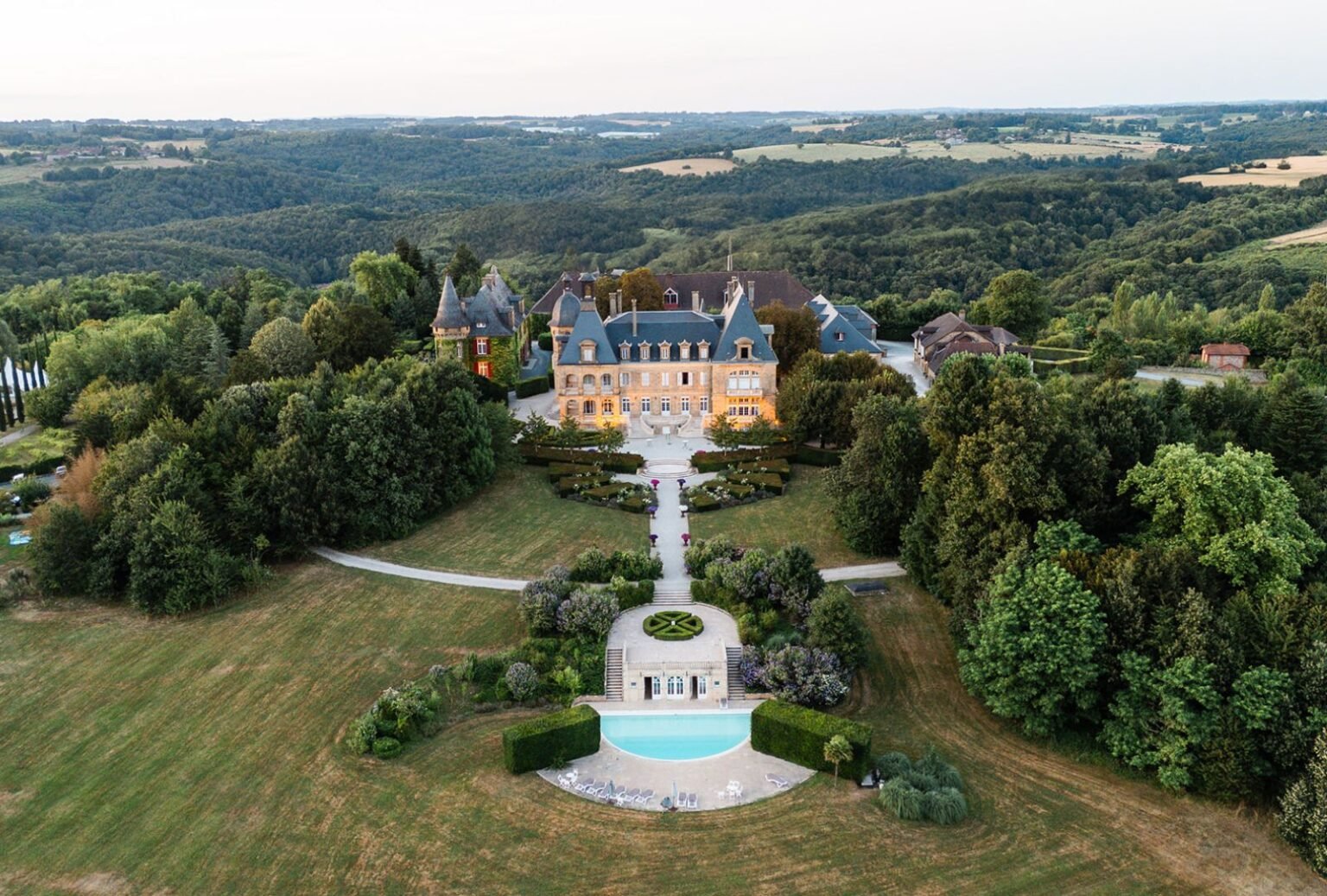 Breathtaking aerial view of Domaine d'Essendiéras, highlighting the estate's French gardens, pool, and expansive countryside.