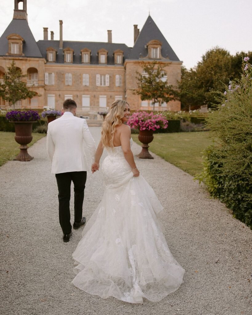 The couple gazes at each other in front of the venue’s grand entrance, the charm of Domaine d'Essendieras enhancing the romance.