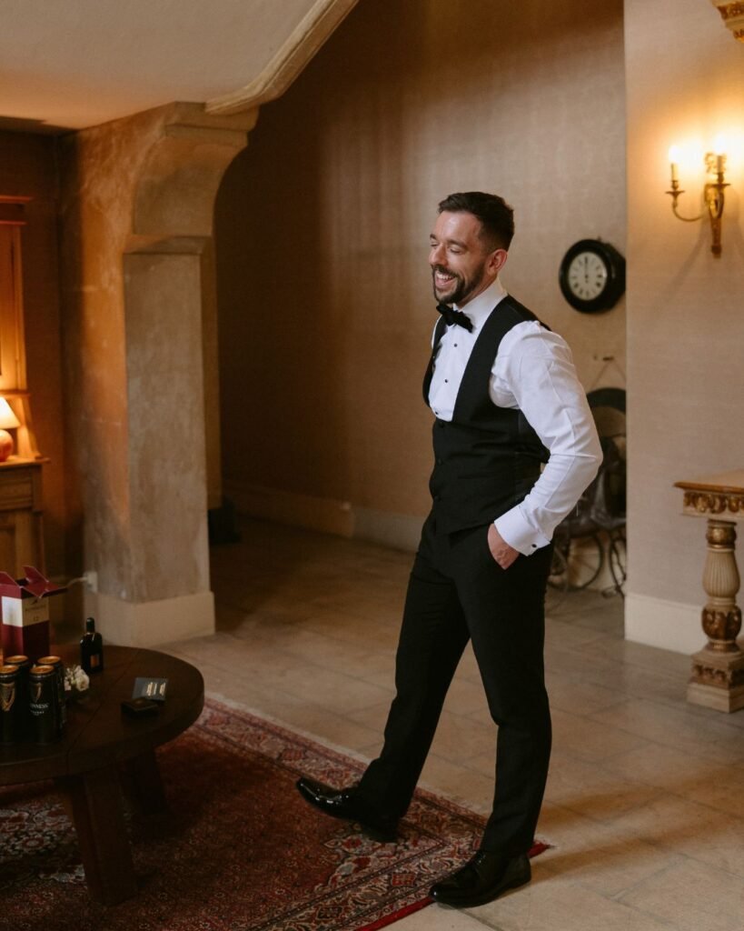 The groom adjusts his suit indoors at Domaine d'Essendieras, captured in a moment of quiet anticipation before the ceremony.