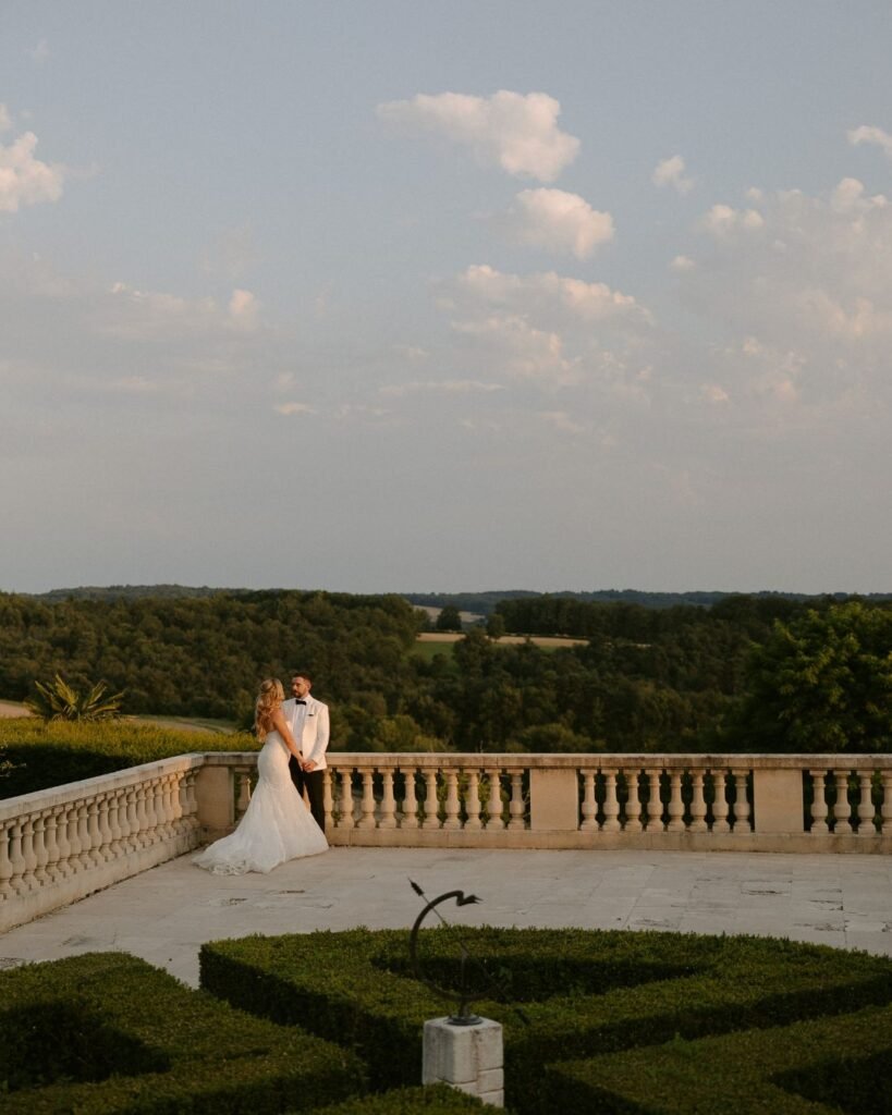 A romantic moment between the couple on the terrace of Domaine d'Essendieras, overlooking the rolling countryside at sunset.