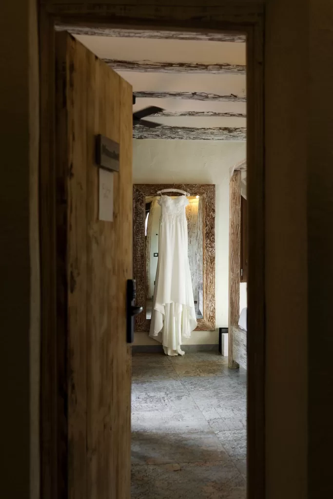Bridal gown hanging elegantly in a rustic room at Mas del Sord before the wedding.