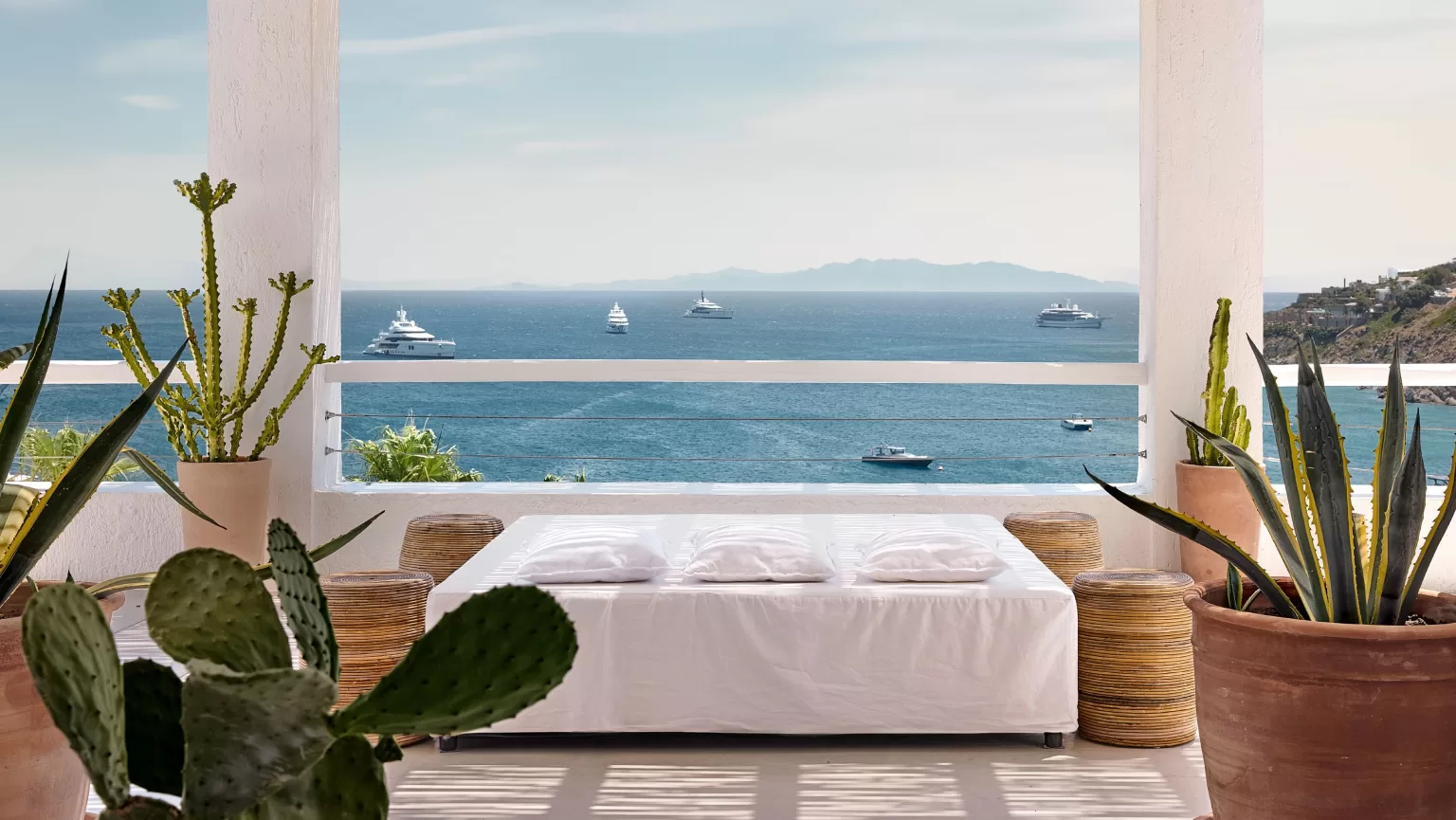 Relaxing terrace lounge at Mykonos Blu with panoramic sea views and lush potted cacti.