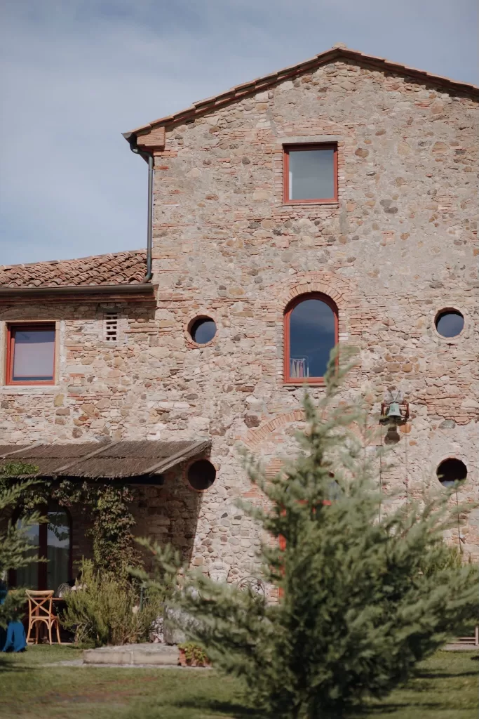 Rustic stone facade of Podere Calvaiola with terracotta accents and greenery
