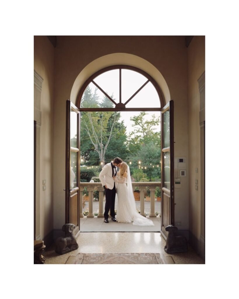 Bride and groom stand on Villa Mangiacane’s grand balcony, gazing at the Tuscan landscape.
