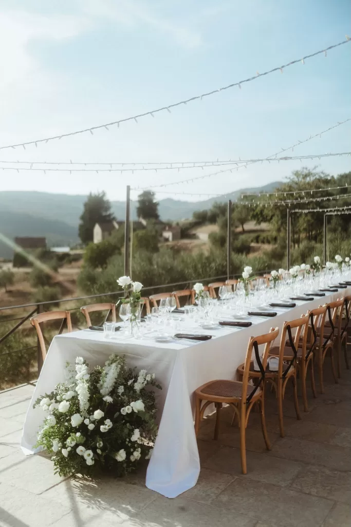 Long banquet tables set with glassware and flowers for an outdoor wedding reception at Castello del Trebbio.