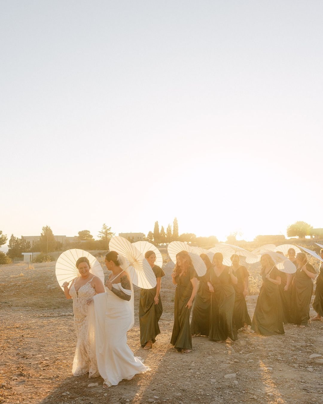 A bride stands in the soft sunset light, her veil flowing gently in the breeze over the Cypriot coastline, captured by Karina Leonenko.