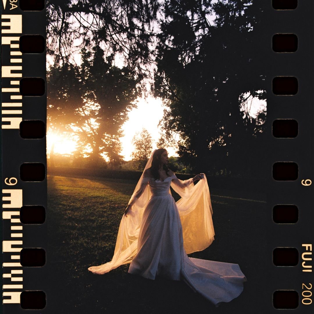 A bride stands silhouetted against a breathtaking sunset, her veil catching the golden light, captured by Studio Fotografico Bacci.