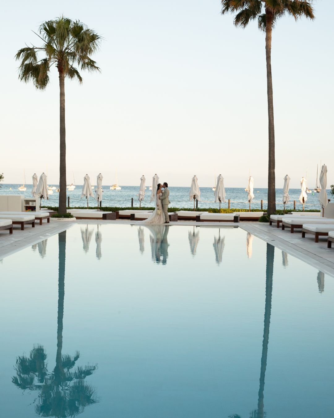A couple posing by the pool, reflecting the tranquility and joy of the day as they embrace and smile together.