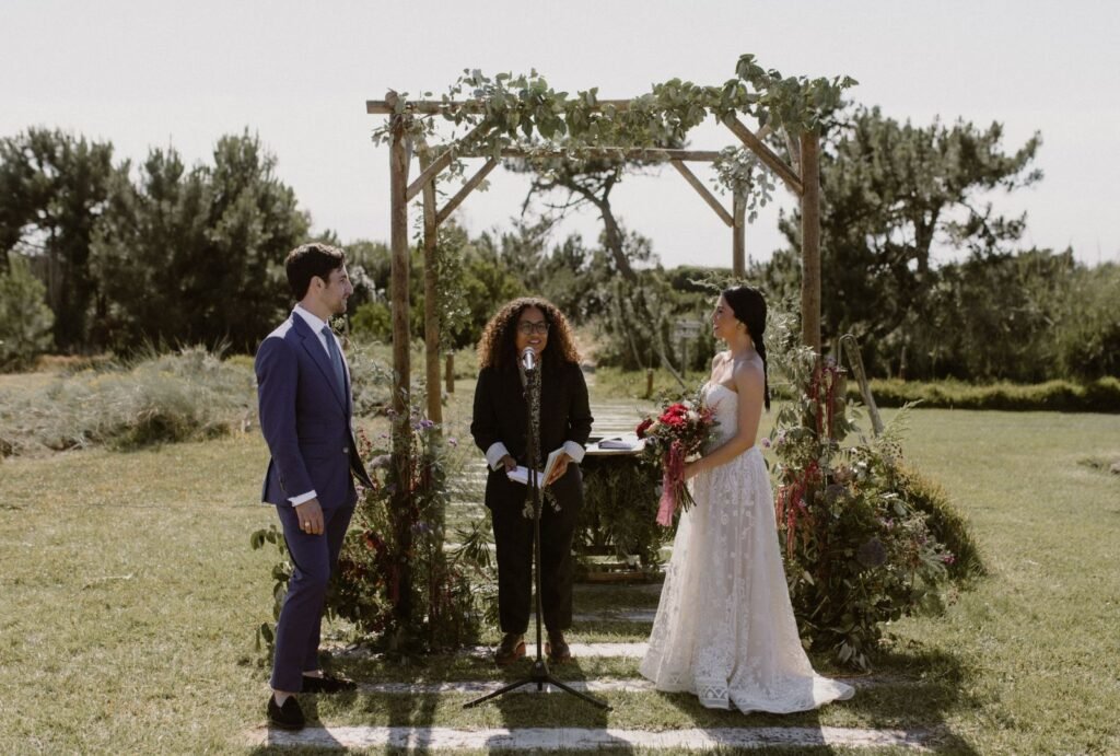 A beautifully decorated ceremony arch at Areias do Seixo, overlooking the ocean with soft floral details and flowing fabric.