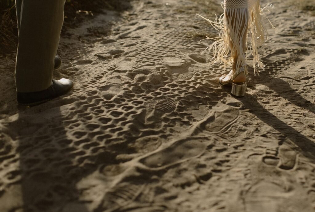 The couple leaves a trail of footprints in the sand as they walk along the shoreline, lost in the moment.