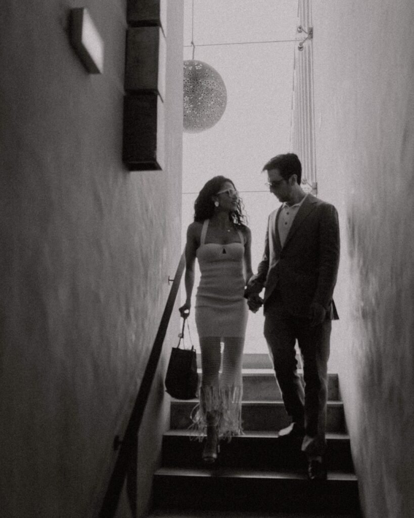 The couple walking down the modern staircase at Areias do Seixo, framed by sleek architectural lines and warm natural light