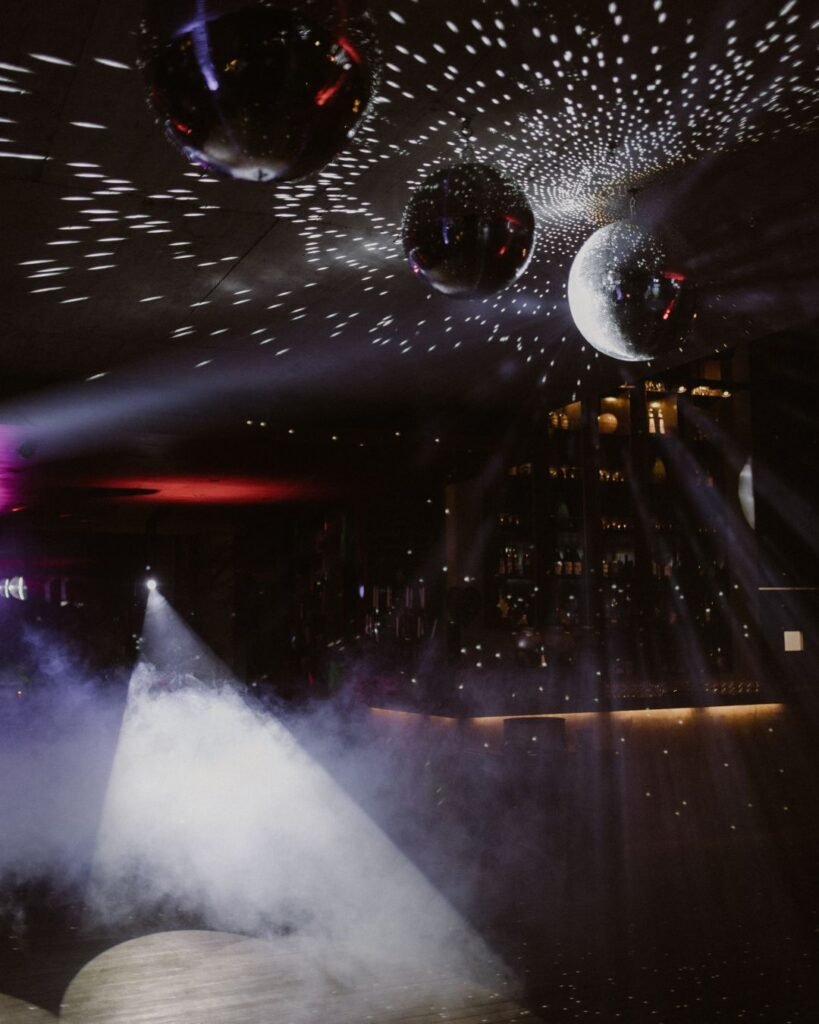 The dancefloor at Areias do Seixo lit by shimmering disco balls, casting reflections for a magical reception atmosphere.