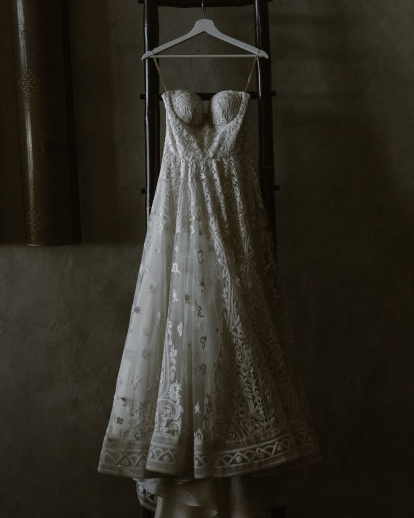 A wedding dress elegantly hung up near a window at Areias do Seixo, softly illuminated by natural light before the ceremony.