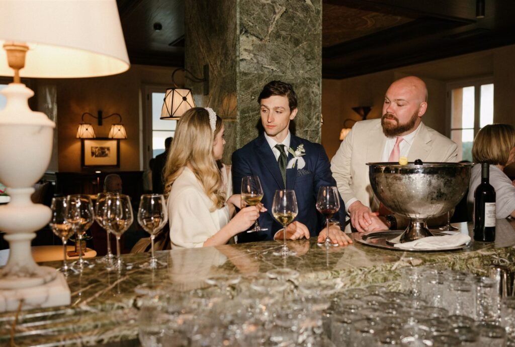 The couple shares a quiet moment at the elegant bar of Rosewood Castiglion del Bosco, sipping cocktails in a warm ambiance.