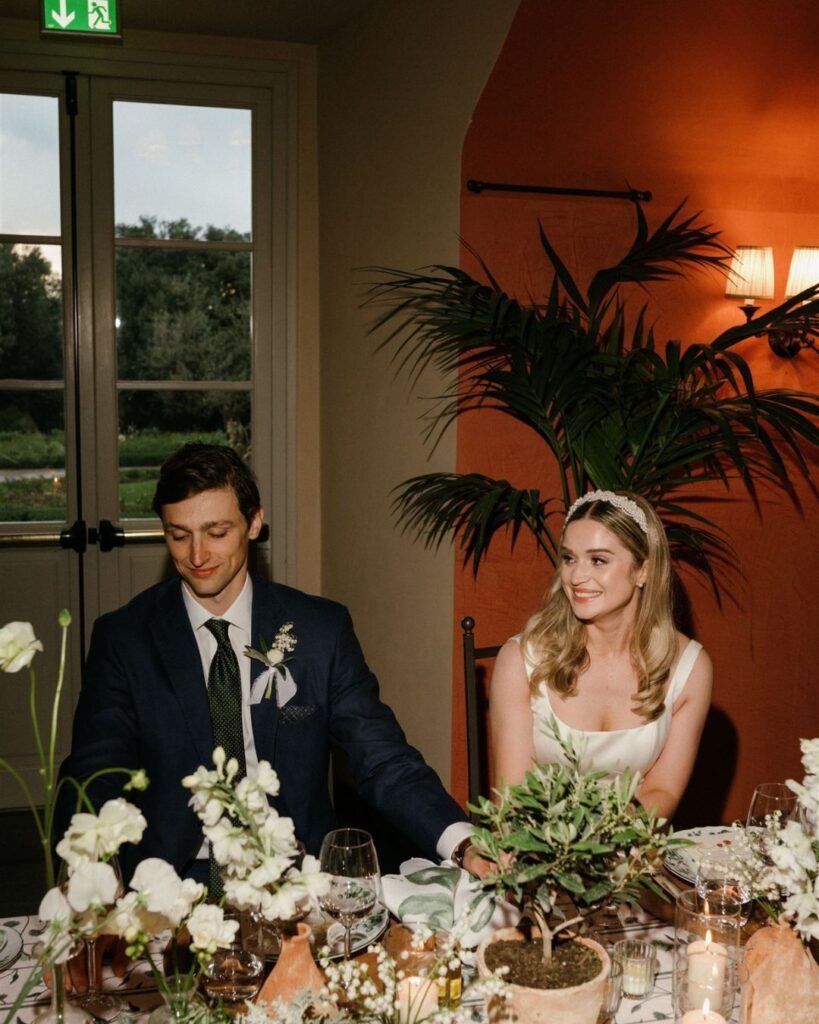 The newlyweds share a private moment at their reception table, surrounded by candlelight and elegant floral decor.