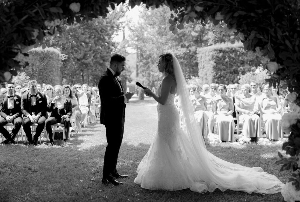 The newlyweds share their first kiss under an elegant floral arch, surrounded by the charm of Domaine d'Essendieras.