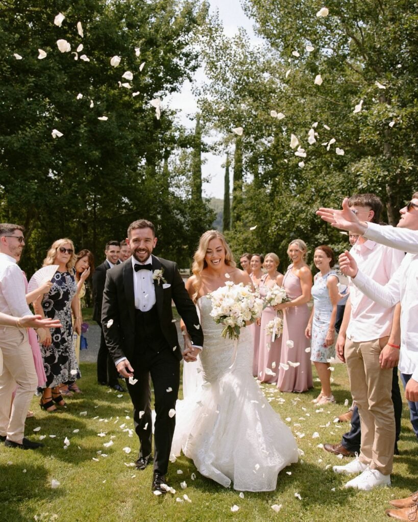 The couple walks hand in hand as guests shower them with confetti, capturing a joyful post-ceremony moment at Domaine d'Essendieras.