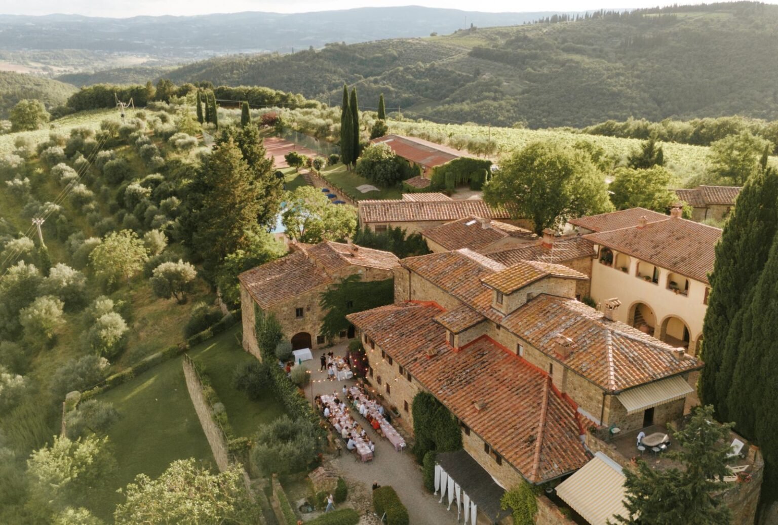 A breathtaking aerial view of Quercia al Poggio, surrounded by rolling Tuscan hills and vineyards.