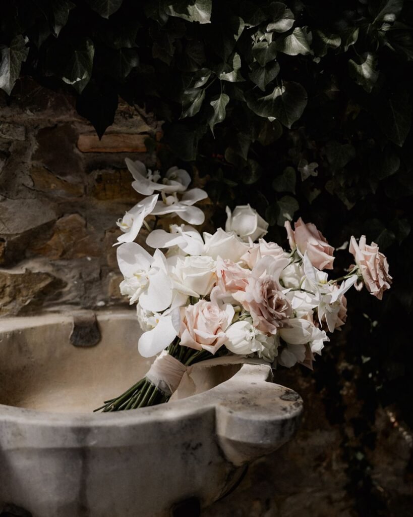 A romantic close-up of a bridal bouquet featuring soft pastel roses and wild greenery.