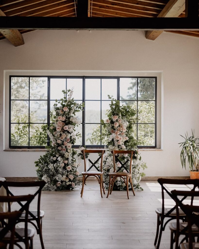 A stunning ceremony arch adorned with white florals against the rustic backdrop of Quercia al Poggio.