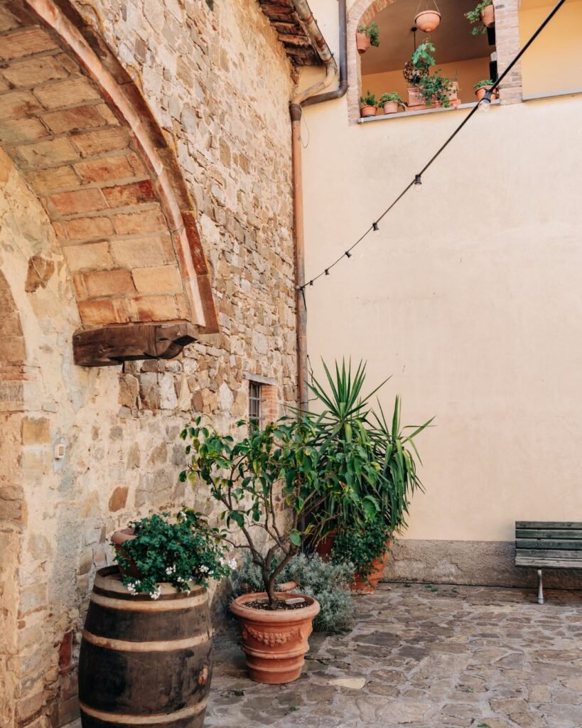 The charming stone courtyard of Quercia al Poggio, bathed in golden sunlight and framed by historic walls.