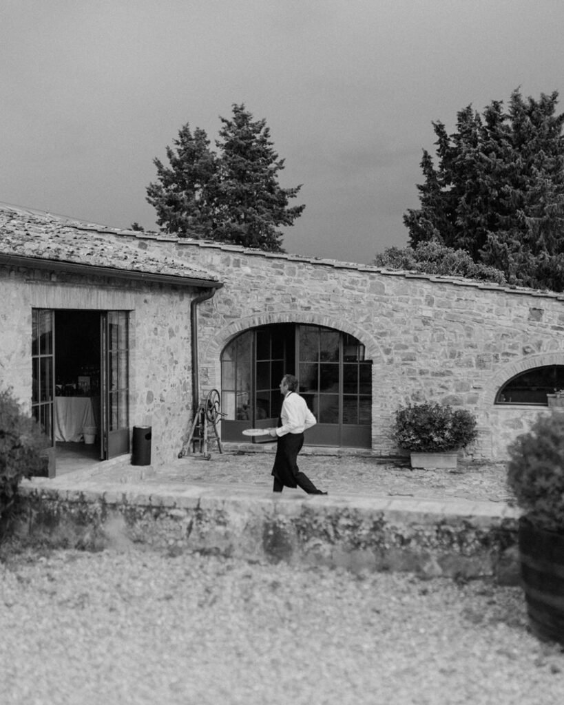 A waiter elegantly carrying plated dishes at a Quercia al Poggio wedding reception.