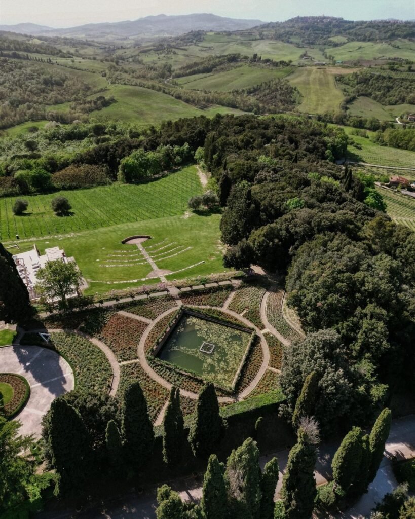 An aerial view of the lush gardens at Rosewood Castiglion del Bosco, framed by cypress trees and elegant pathways.