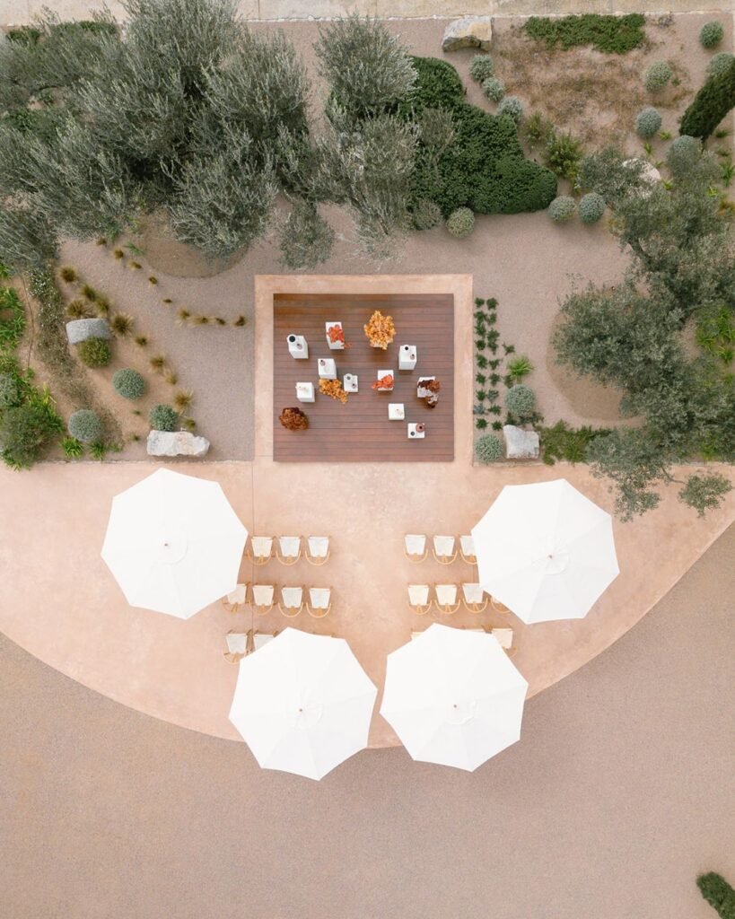 Wooden ceremony chairs arranged beneath cream umbrellas at Finca Morneta, captured by Puy Cermeno.