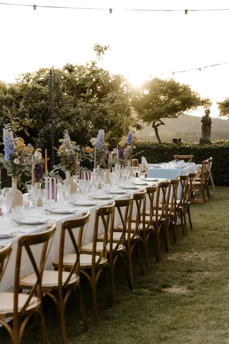 Long wedding table at Borgo Stomennano glowing in golden hour light, framed by floral centerpieces and string lights.