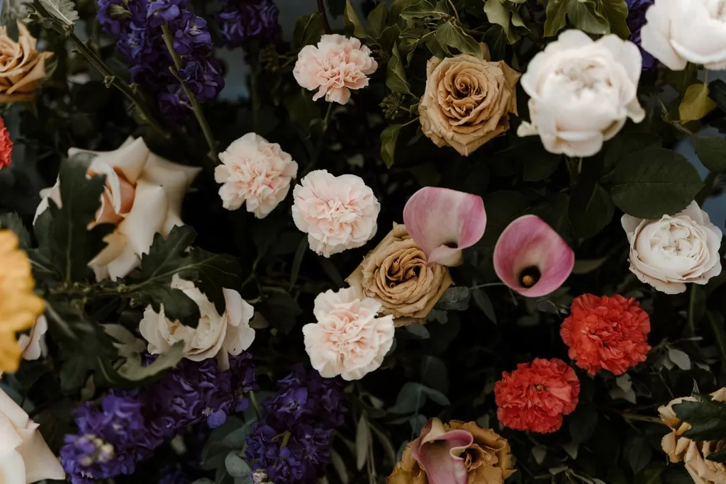 Lush floral arrangement with roses, carnations, and calla lilies in warm and jewel tones at Borgo Stomennano.