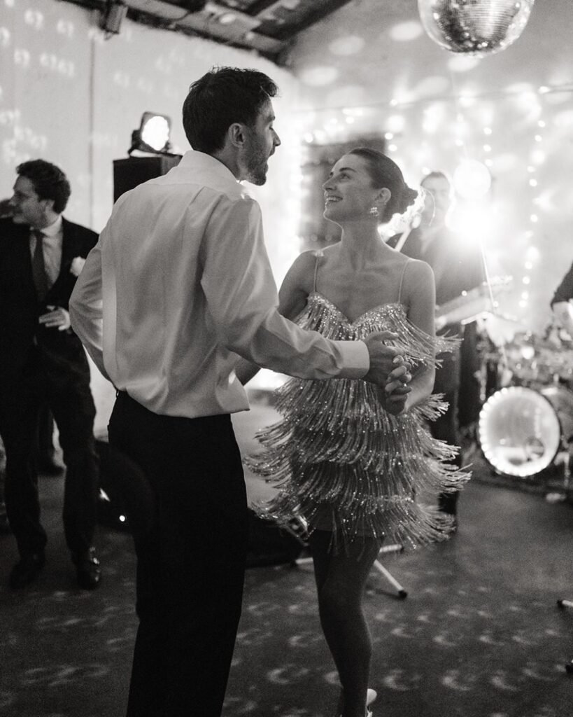 Bride and groom dancing joyfully under a disco ball at Château Rigaud, surrounded by friends and glowing lights.
