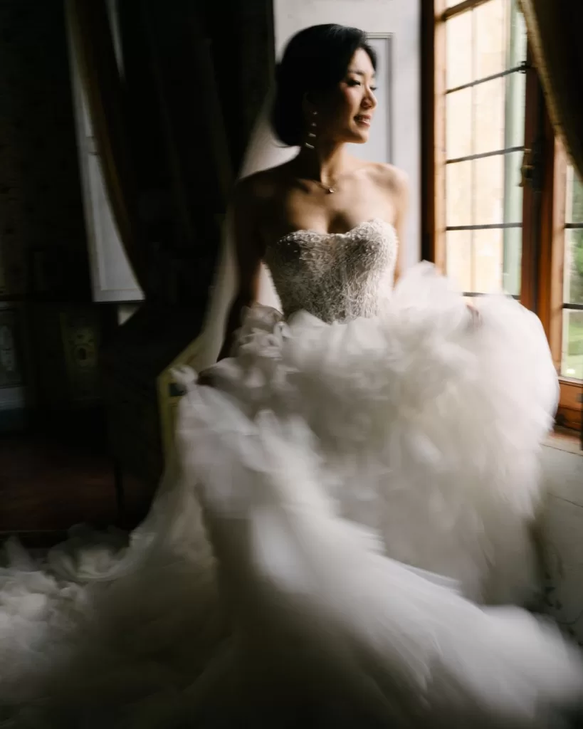 The bride holds a bouquet of soft pastel flowers, standing in the gardens of Villa di Geggiano.