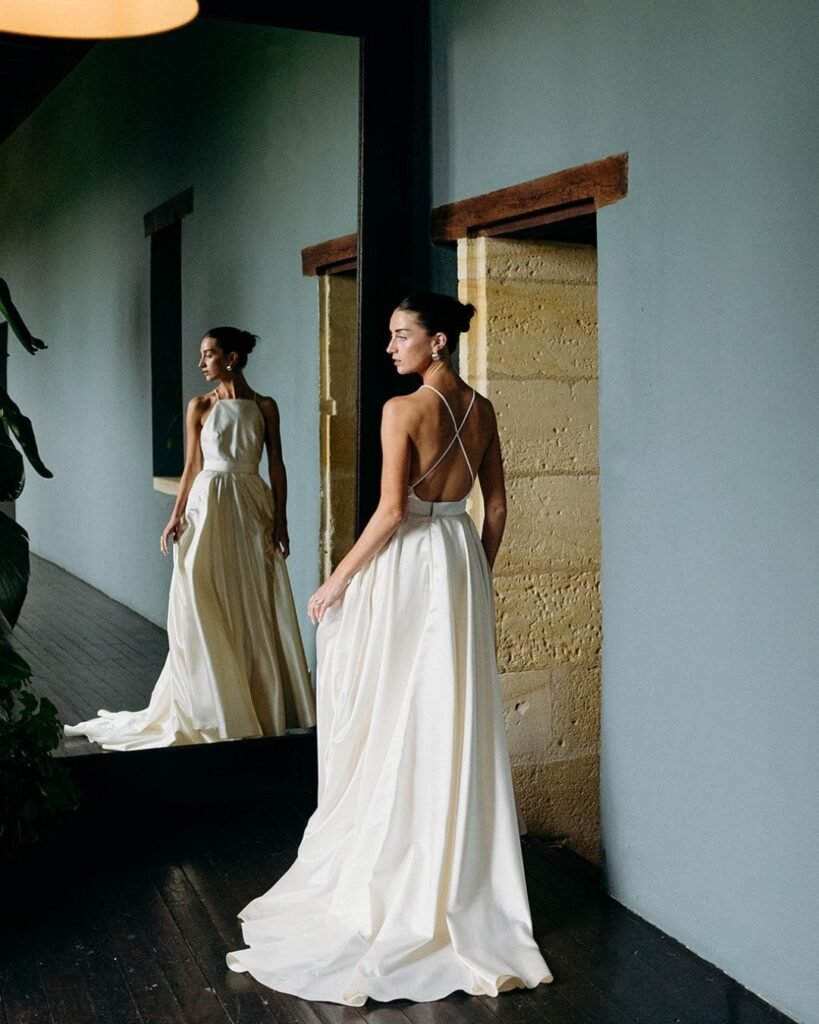 Bride in a flowing ivory gown gazing at her reflection at Château Rigaud, captured by Cleya Asulon.