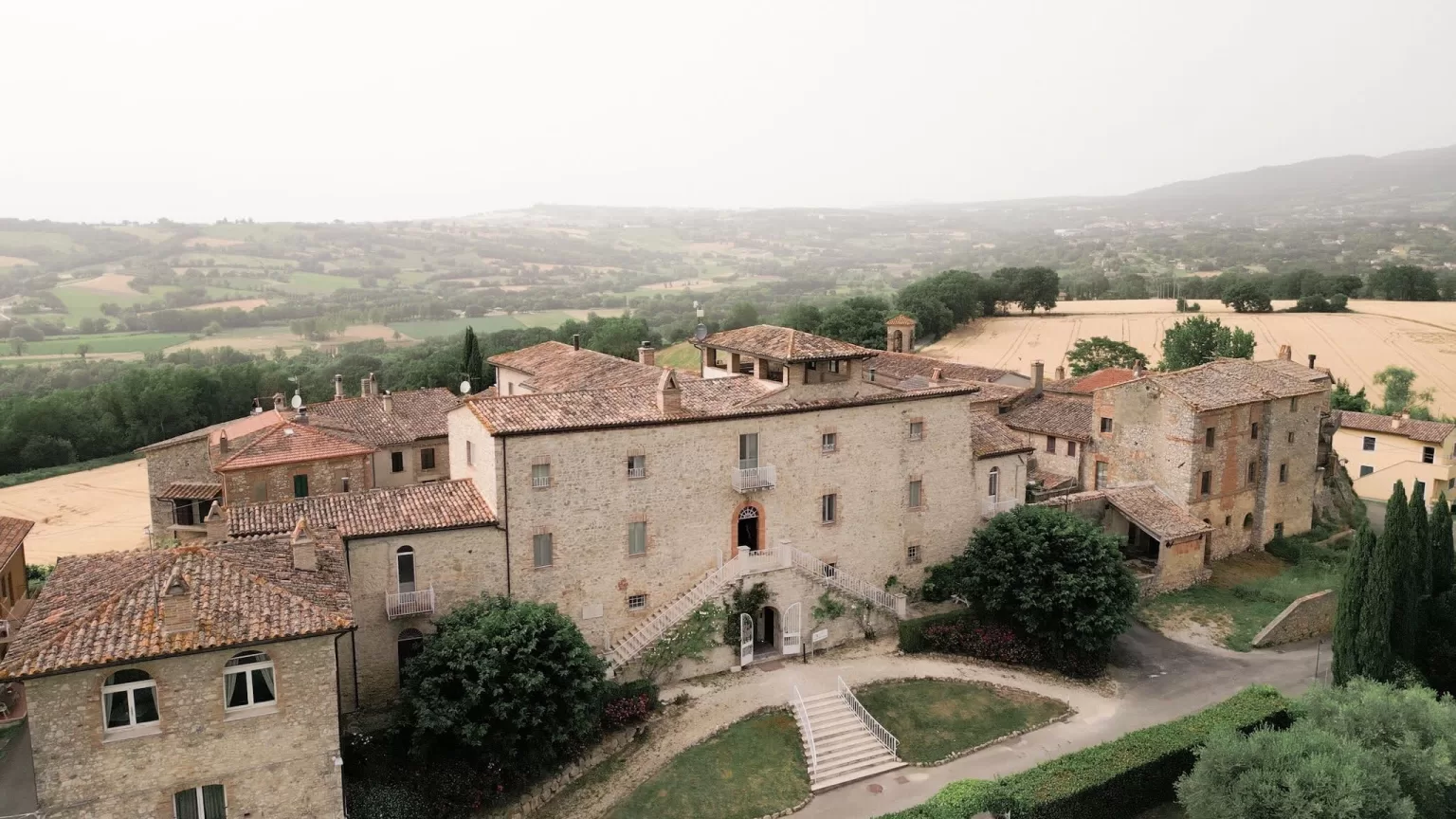 Aerial view of Castello di Montignano with its historic buildings and sweeping countryside landscape.