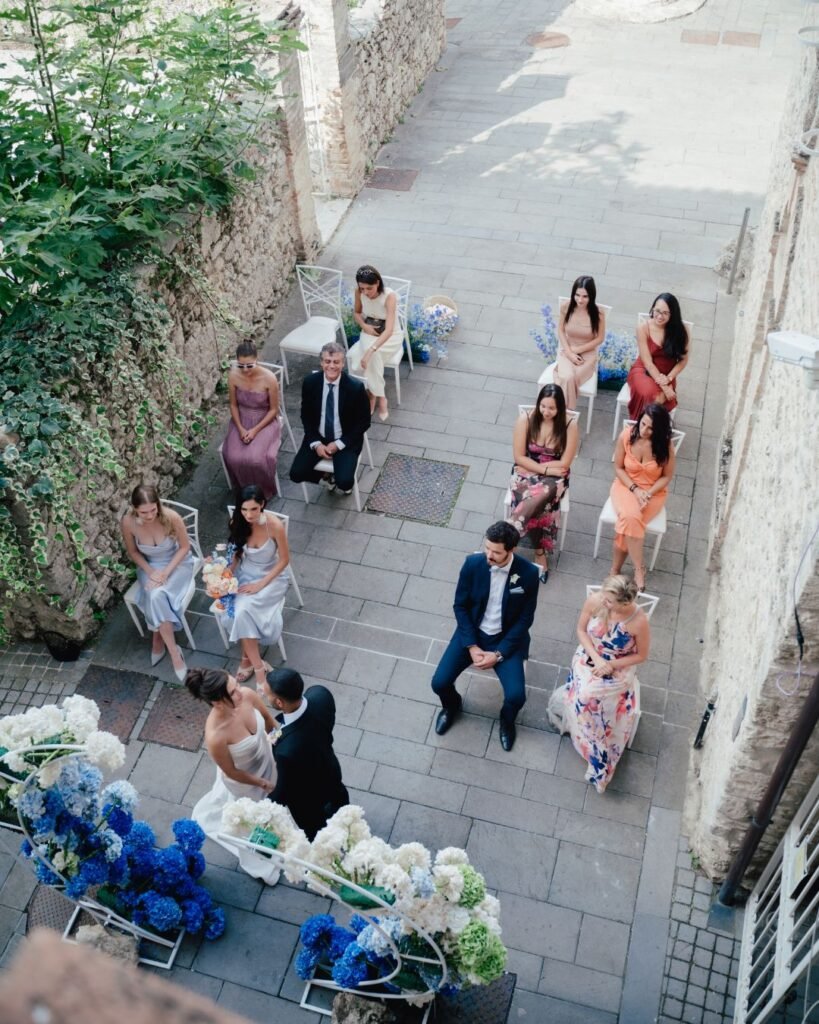 Aerial view of the wedding ceremony at Castello Montignano with guests seated along a narrow historic courtyard.