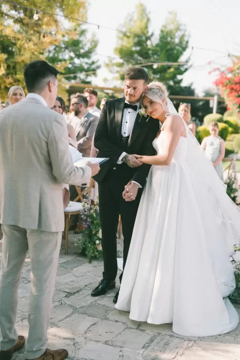 Bride and groom hold hands during an emotional wedding ceremony at Liopetro, with guests watching on.
