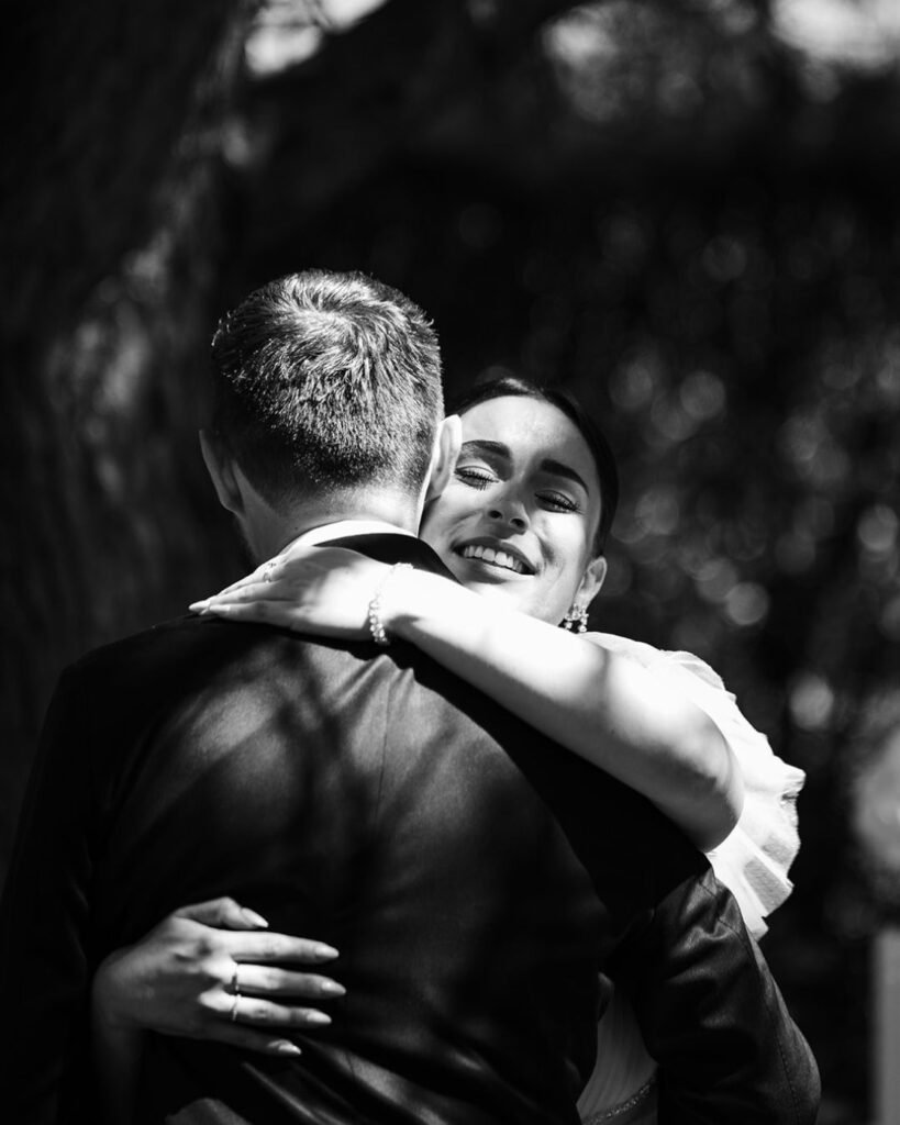 Emotional black-and-white moment of bride warmly embracing groom, capturing love and intimacy at Domaine d'Essendiéras.