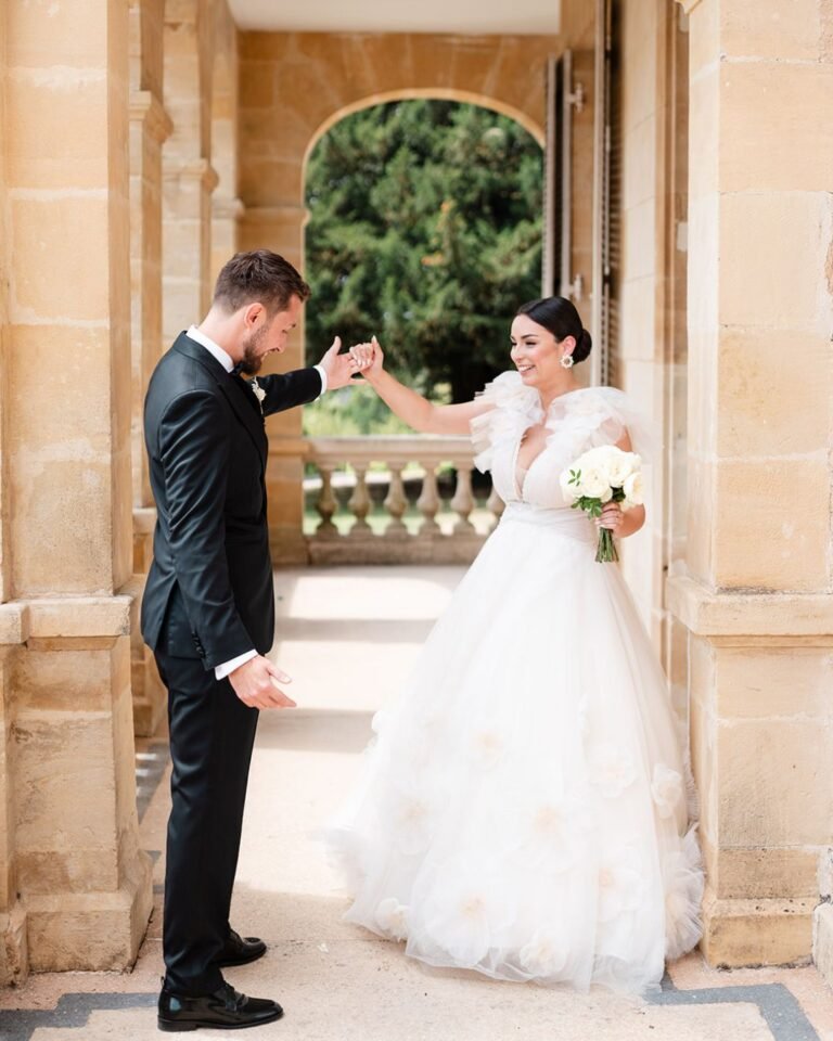 Emotional first look moment between bride and groom beneath an arched doorway at Domaine d'Essendiéras.
