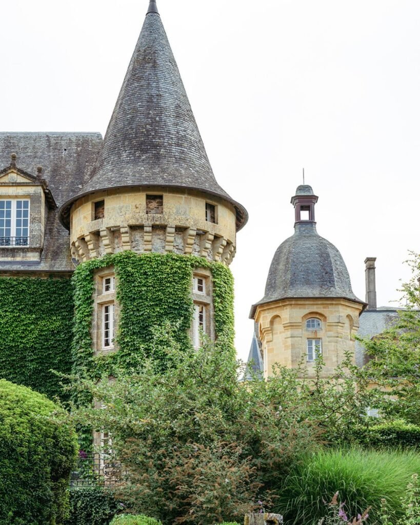 Ivy-covered medieval tower at Domaine d'Essendiéras, surrounded by lush greenery creating a fairytale atmosphere.