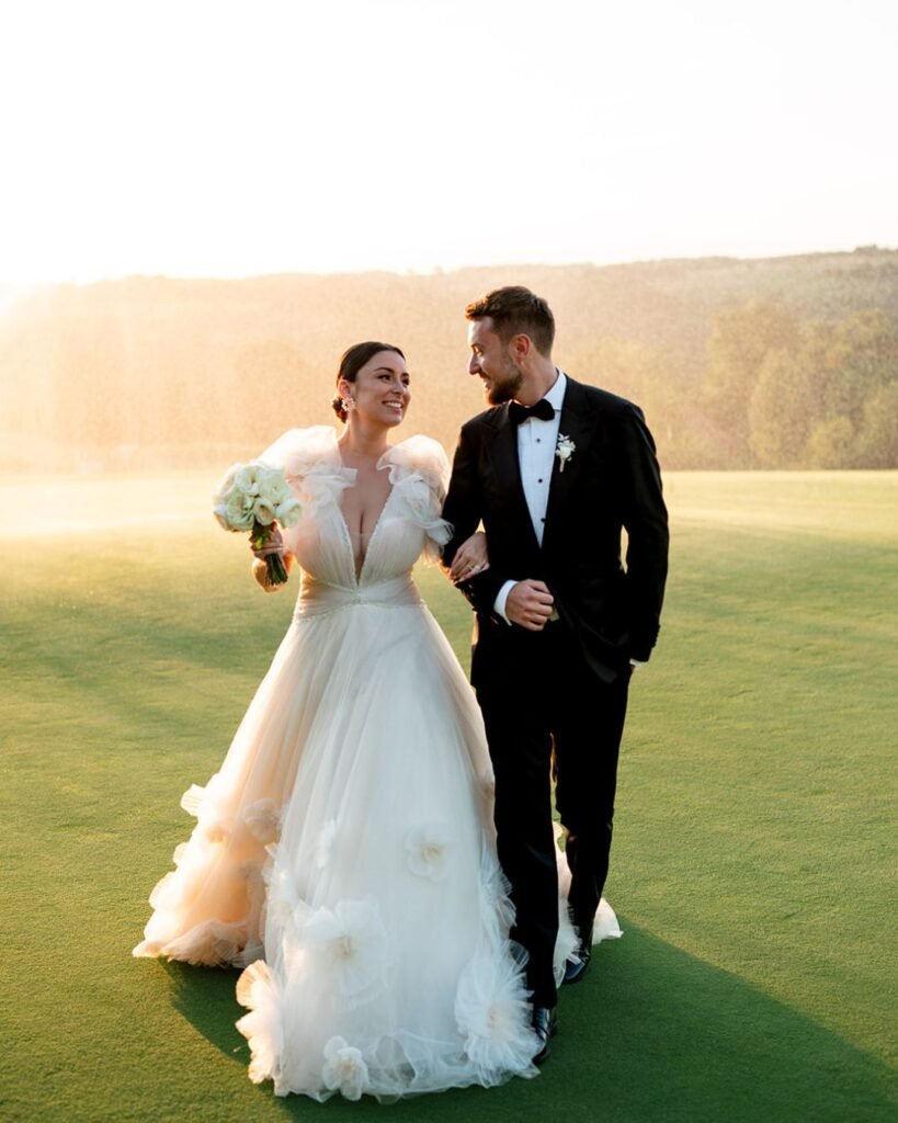 Joyful bride and groom walking arm-in-arm across the grounds of Domaine d'Essendiéras, illuminated by golden sunset.