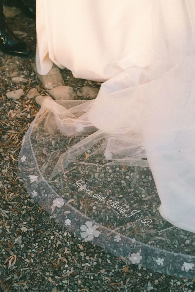 Close-up of the bride’s veil embroidered with “Forever and Always” beside the train of her gown at Liopetro.