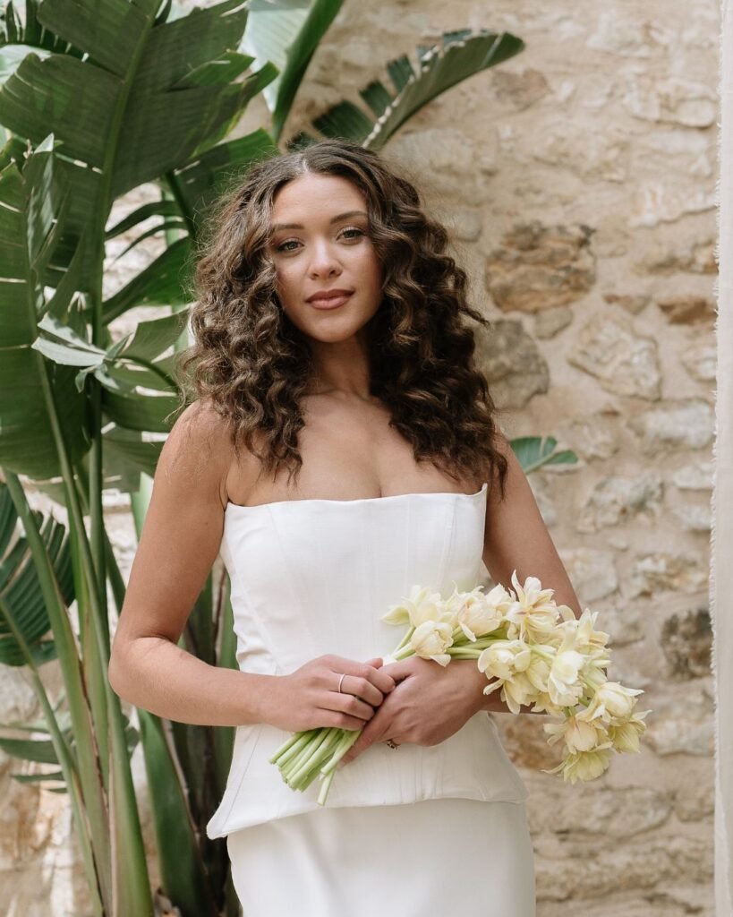 Bridal portrait showcasing a relaxed yet sophisticated bride holding a delicate bouquet, framed by tropical greenery at Finca Morneta.