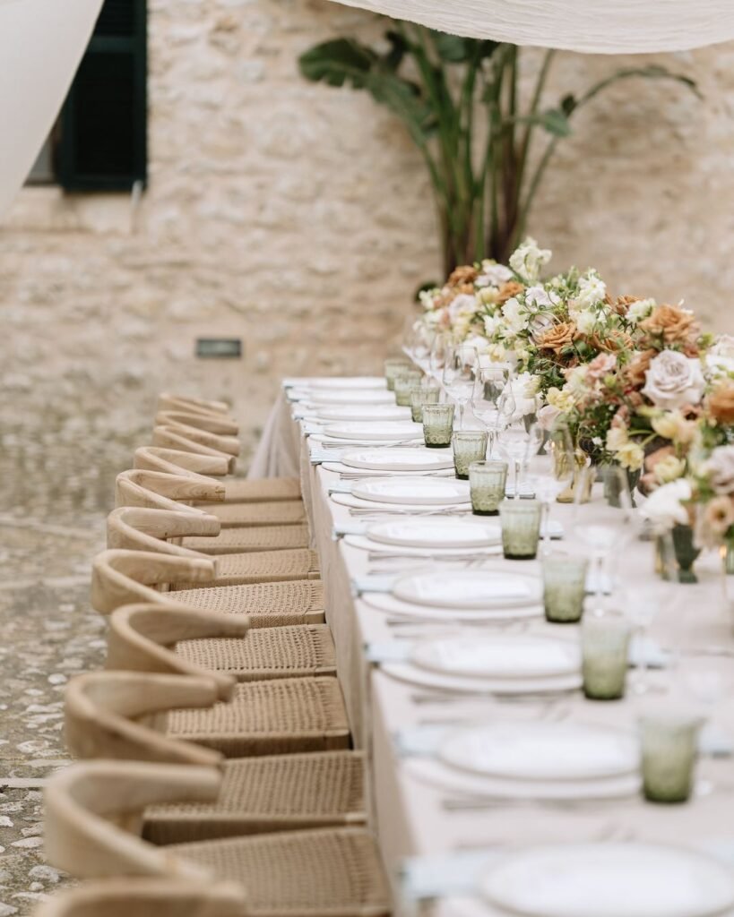 Elegant wedding table decor with pastel florals and rustic chairs in a charming courtyard setting at Finca Morneta, photographed by Sharon Cudworth