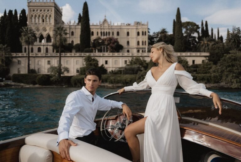 Sophisticated couple cruising Lake Garda on luxury boat with grand Italian villa backdrop, photographed by Lukas Hanifle.