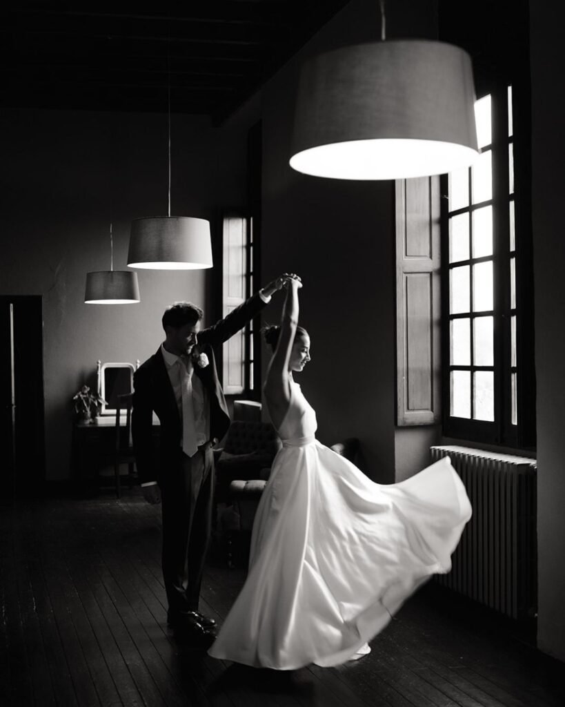 Bride twirling in her gown as the groom leads her in a graceful indoor dance at Château Rigaud.