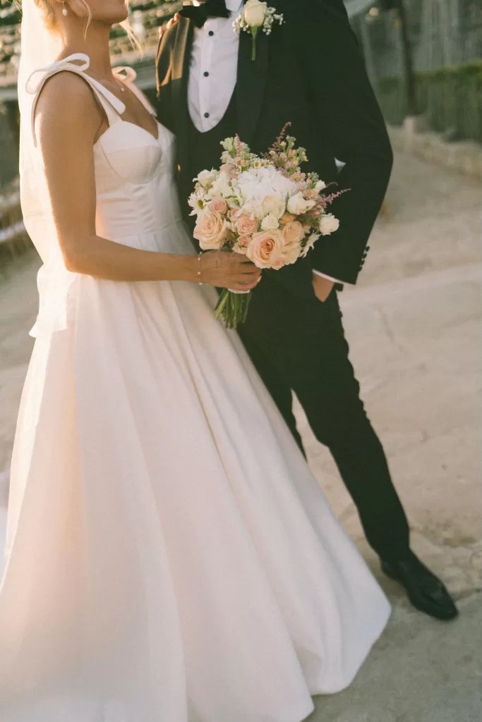 Close-up of bride holding a soft pastel bouquet, framed against her flowing satin gown at Liopetro.