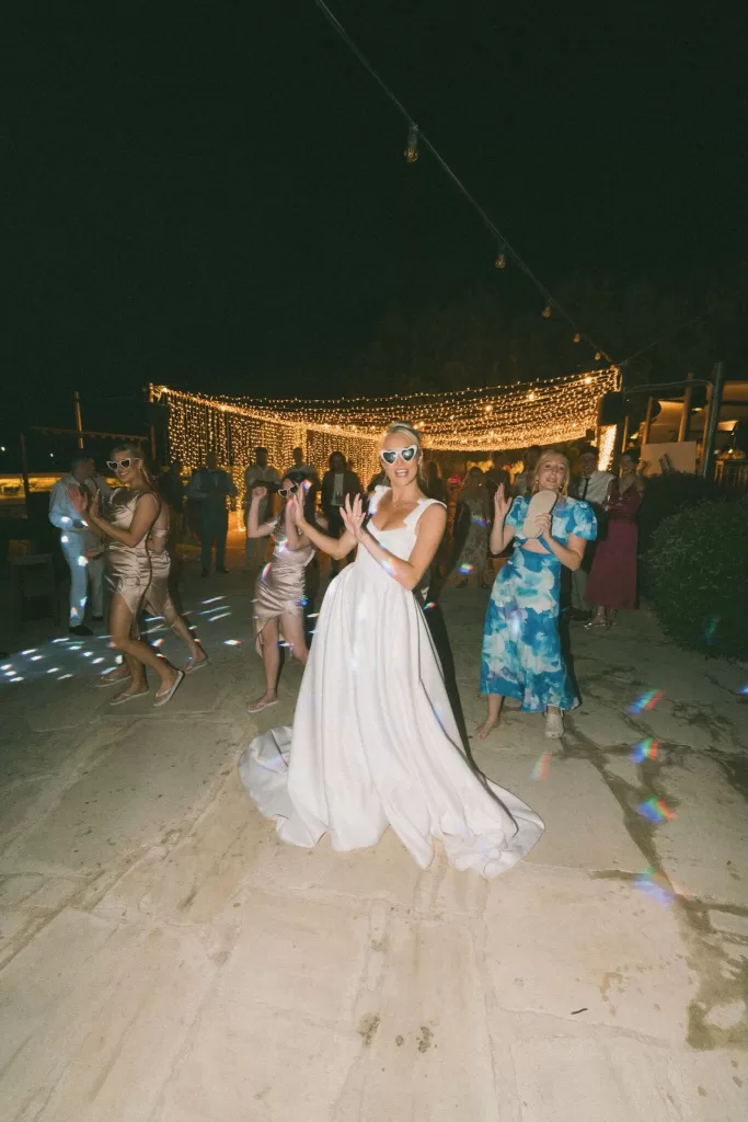 The bride dancing joyfully at night under string lights at Liopetro in Cyprus.