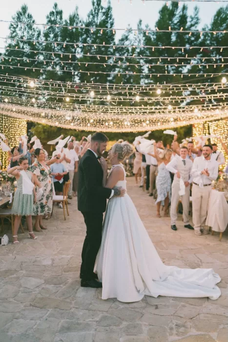 Bride and groom share their first dance under a canopy of fairy lights at Liopetro as guests cheer around them.