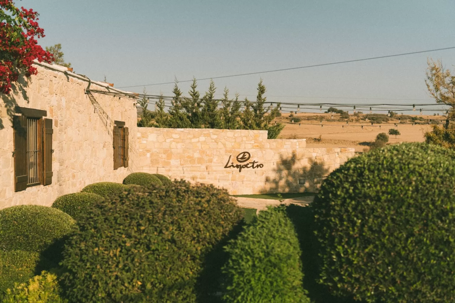Warm afternoon light on Liopetro’s stone facade and landscaped gardens, showing its Mediterranean charm.